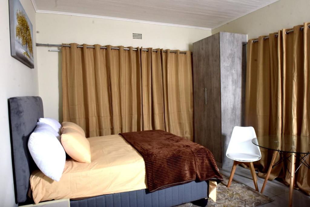 a bedroom with a bed and a table and curtains at Private Guest suite in Ferndale in Johannesburg