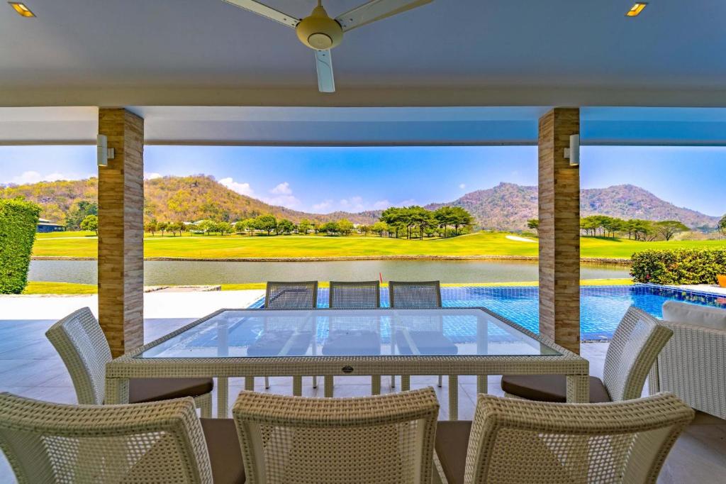 a patio with a glass table and chairs and a golf course at Nice 3BR with Golf Course View - BMG3 in Hua Hin