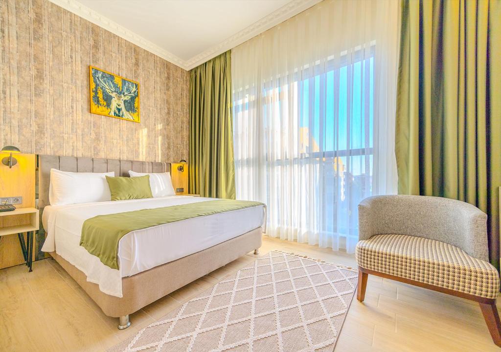 een slaapkamer met een bed, een stoel en een raam bij Ayçiçeği Comfort Otel in Edirne