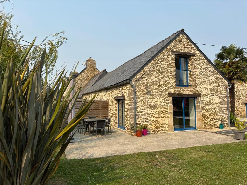 a stone house with a patio and a table at Maison Onze calme en bord de Rance in Plouër-sur-Rance