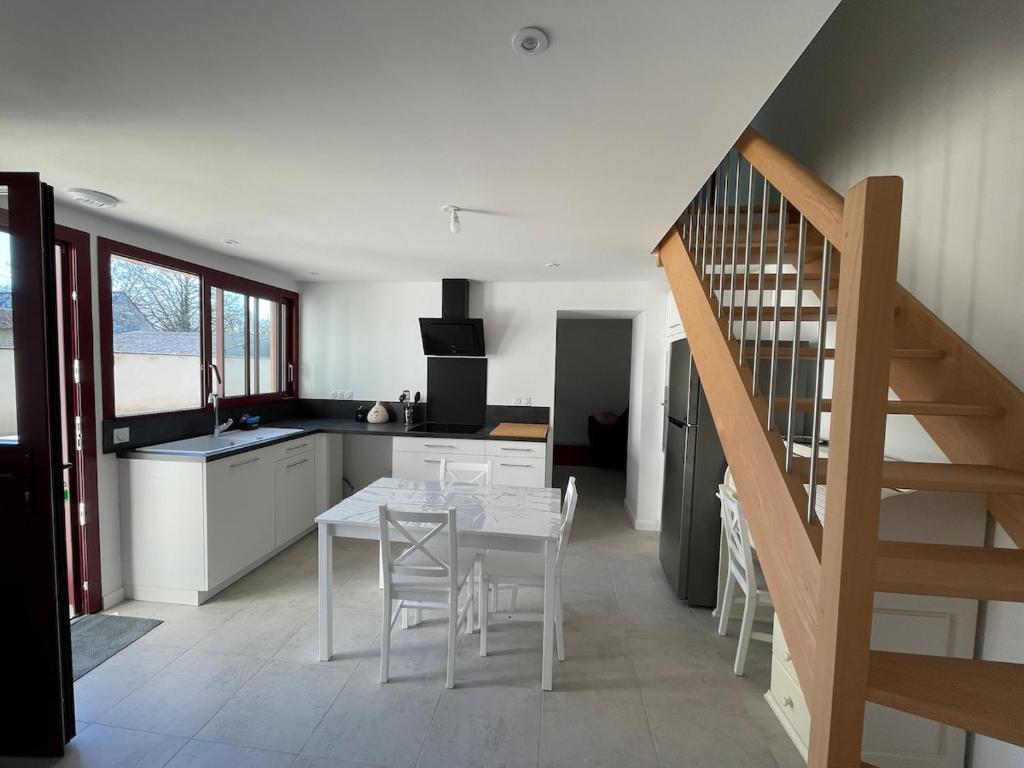 a kitchen with a table and chairs and a staircase at Maison au cœur du pays de Rabelais in Lerné