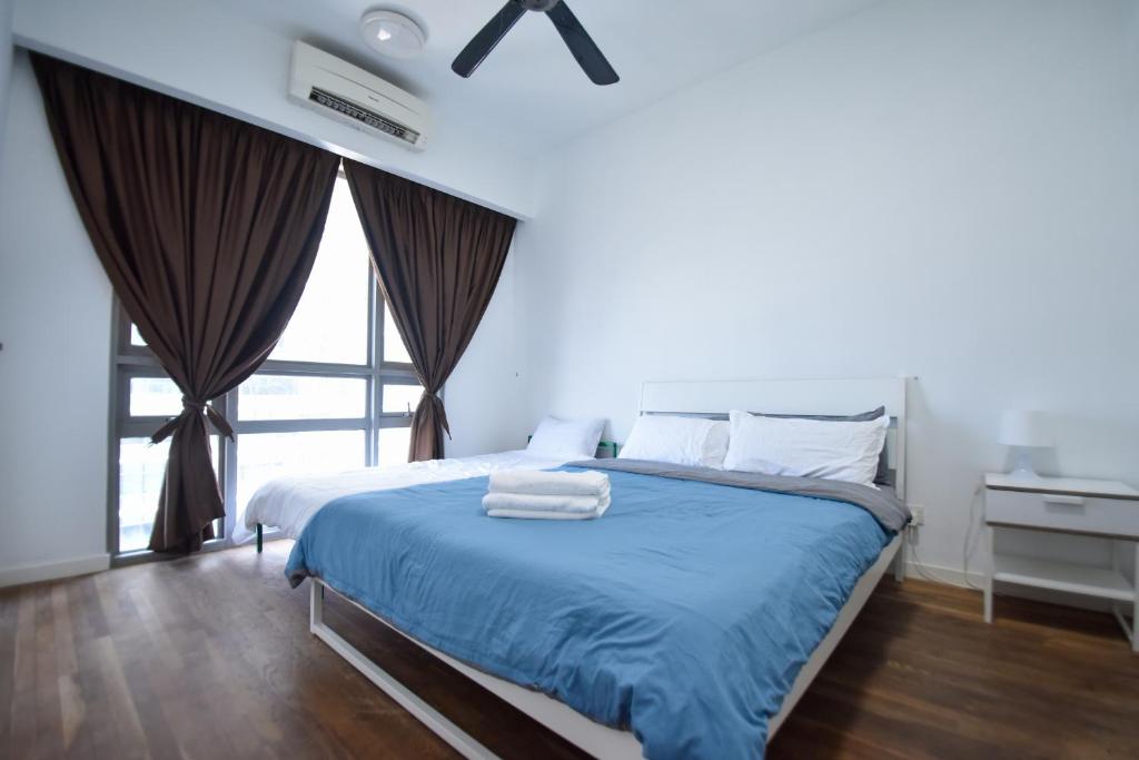 a bedroom with a bed with blue sheets and a window at Cascades Residency in Kota Damansara in Petaling Jaya