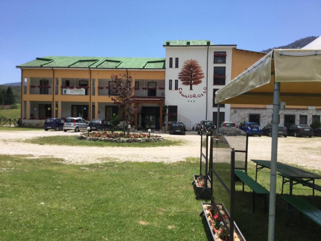 a large building with a building with cars in front of it at Hotel Faggio Rosso in Pescasseroli
