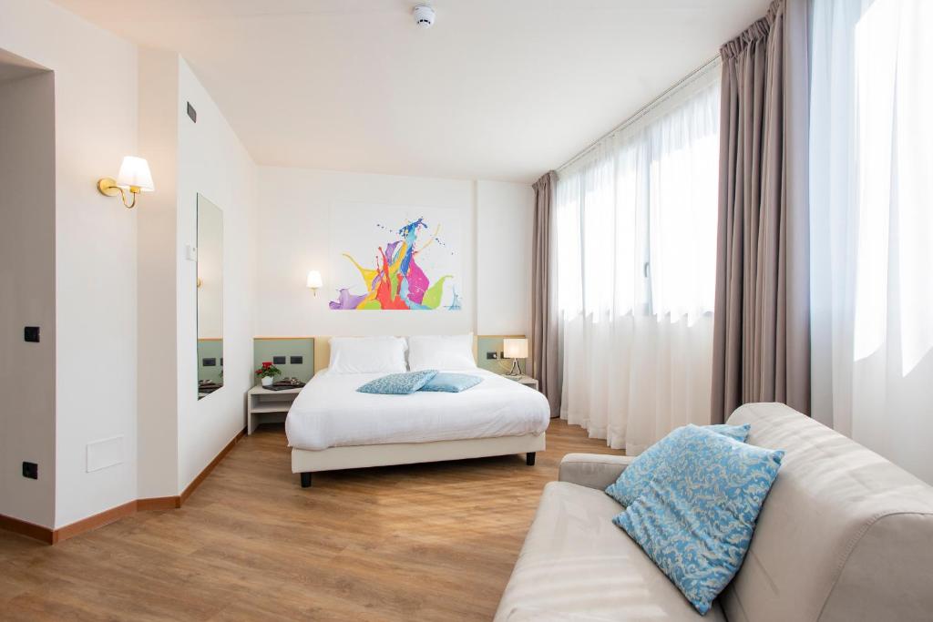 Un dormitorio blanco con una cama y un sofá. en AN Hotel Milano San Donato, en San Donato Milanese
