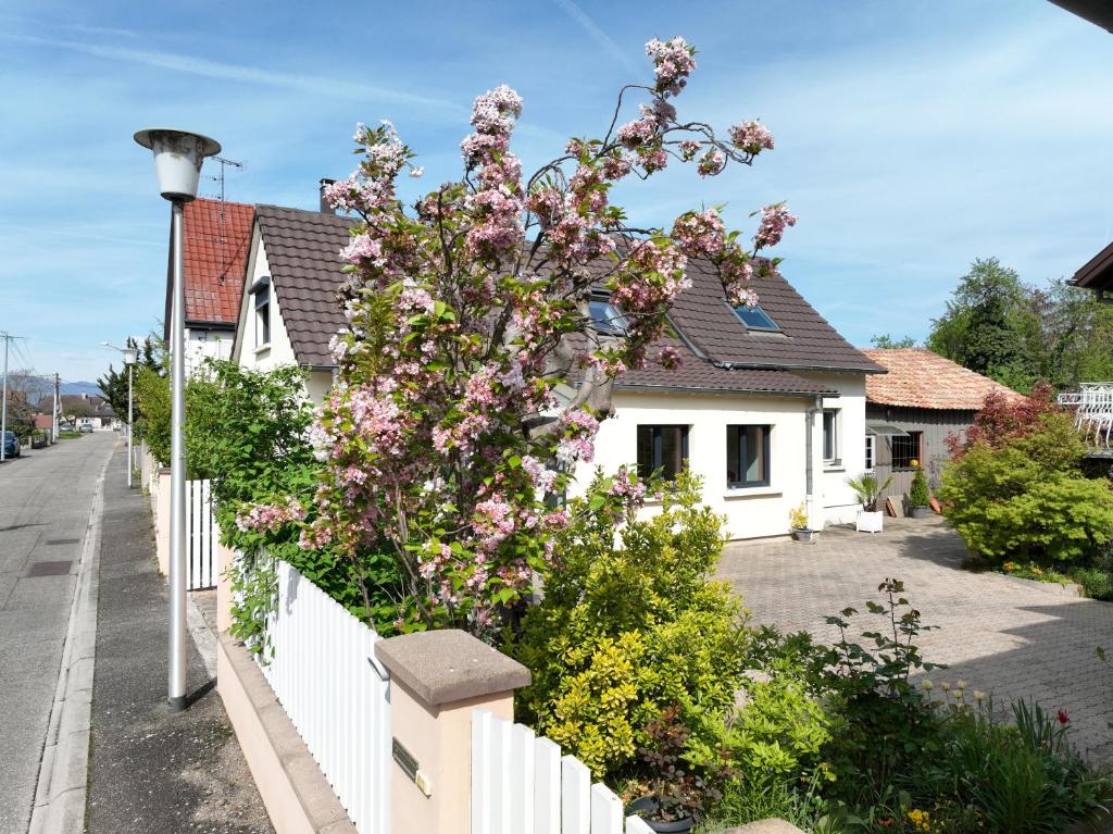 una recinzione bianca con fiori rosa su una casa di Maison de village près de Colmar de 90 m2 a Horbourg