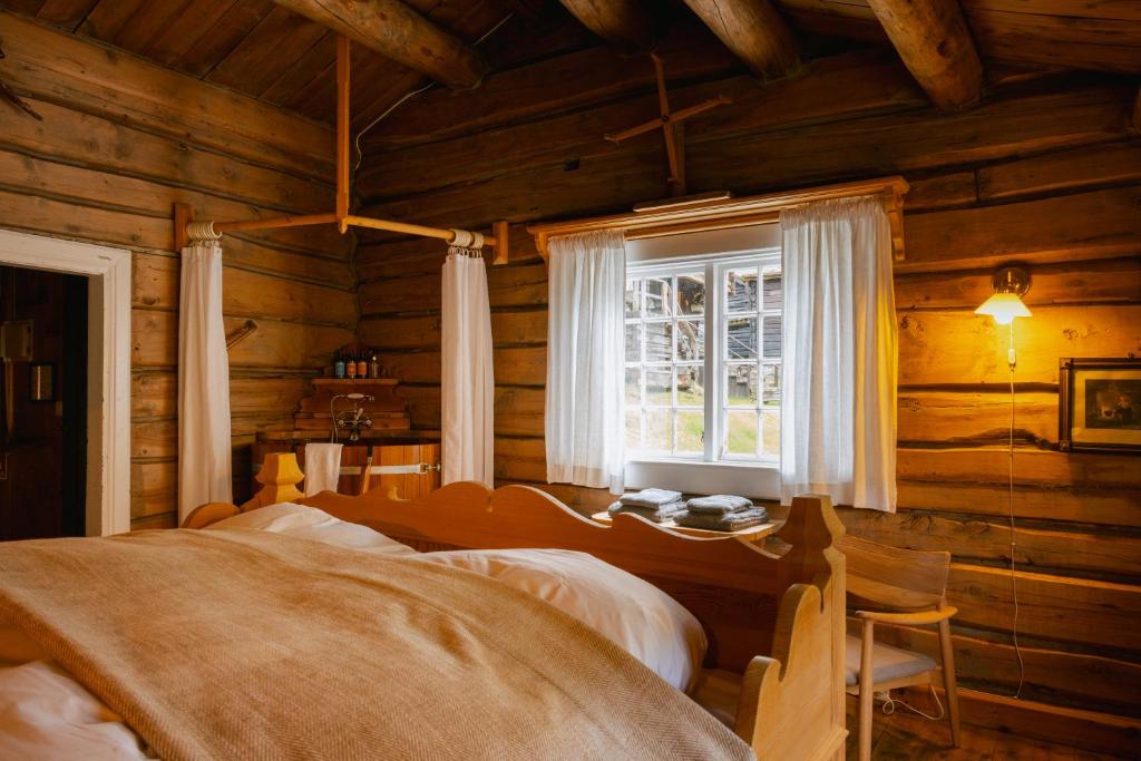 una camera da letto in una baita di tronchi con finestra di Røisheim Hotel & Skysstasjon a Lom