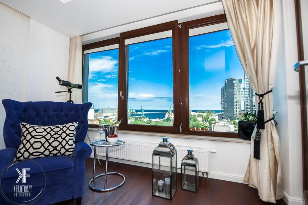 a living room with a blue chair and a large window at Apartament Transatlantyk in Gdynia