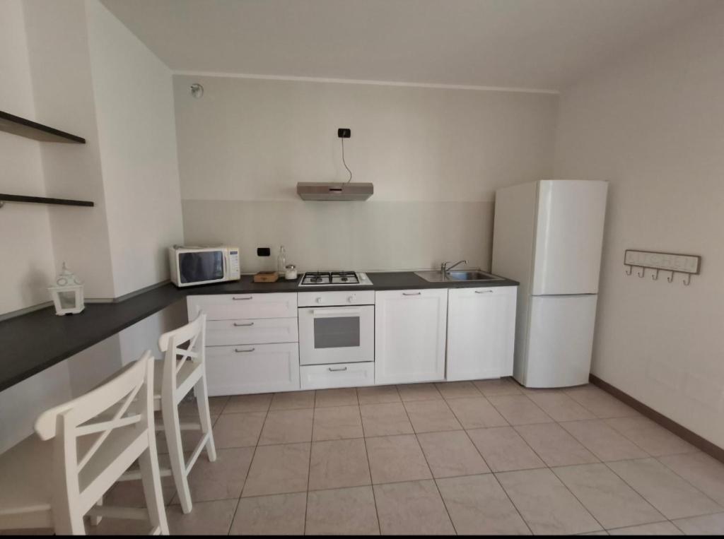 Una cocina con electrodomésticos blancos y un refrigerador blanco. en Bergamo's little flat, en Villa dʼAlmè