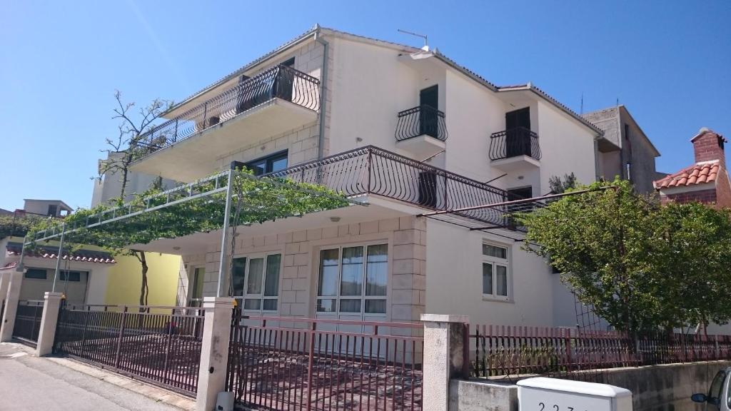 a white house with a fence in front of it at Beautiful Apartment Jukic in Podstrana