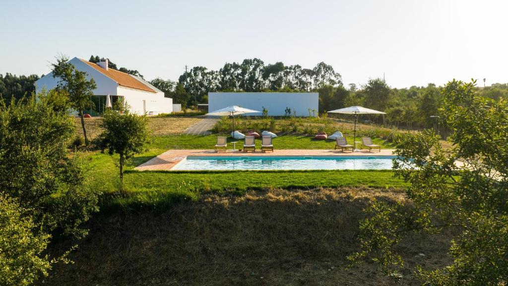 a pool with chairs and umbrellas in a yard at Casa do Regadio in Zambujeira do Mar