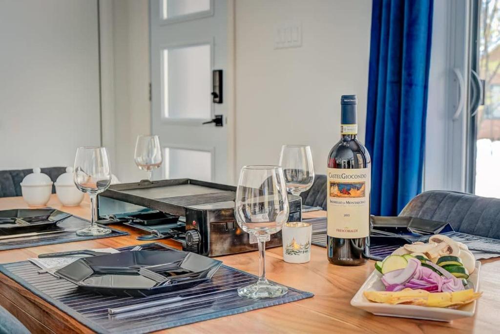 un tavolo con una bottiglia di vino e bicchieri da vino di Chalet Le Baikal a Pont-Rouge