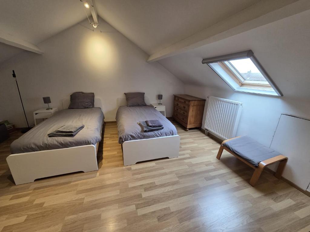 - une chambre mansardée avec 2 lits et une fenêtre dans l'établissement Bel-étage cosy 2 chambres proche Charleroi-Airport, à Charleroi