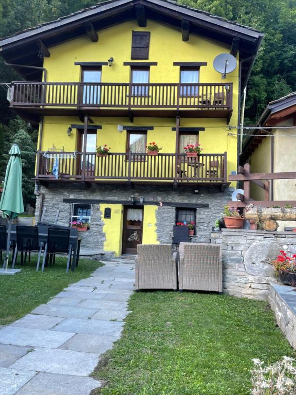 a yellow house with a balcony and some chairs at Le Flocon de neige in Valtournenche