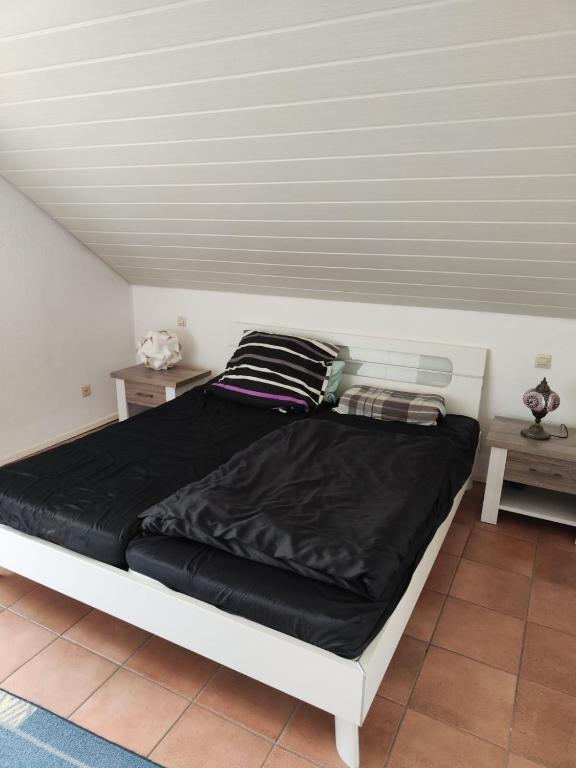 a bed with a black blanket and two pillows at Zimmer mit Weitblick in Weinregion in Bad Kreuznach