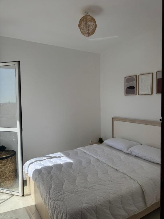 a white bedroom with a bed and a mirror at Fès comfort stay in Fès