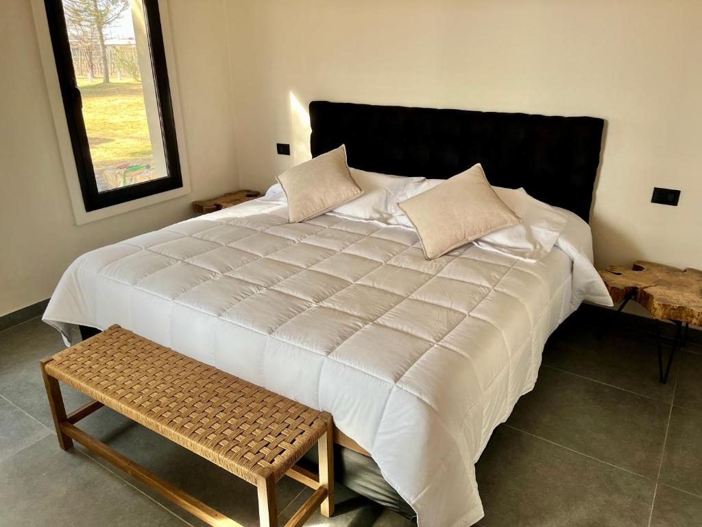 un grande letto bianco con panca in una stanza di Finca Torcivia Luna a Vista Flores