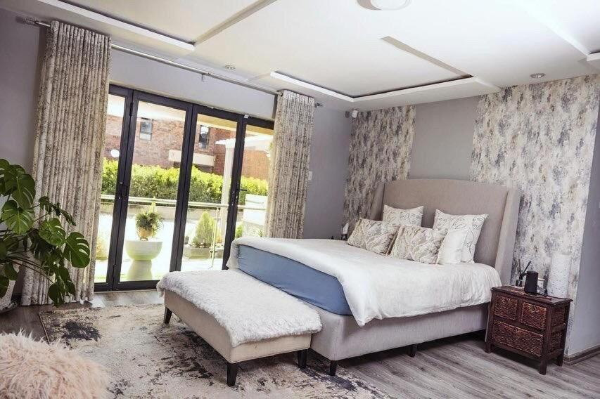 a bedroom with a bed and a chair and windows at Home away from Home in Maseru