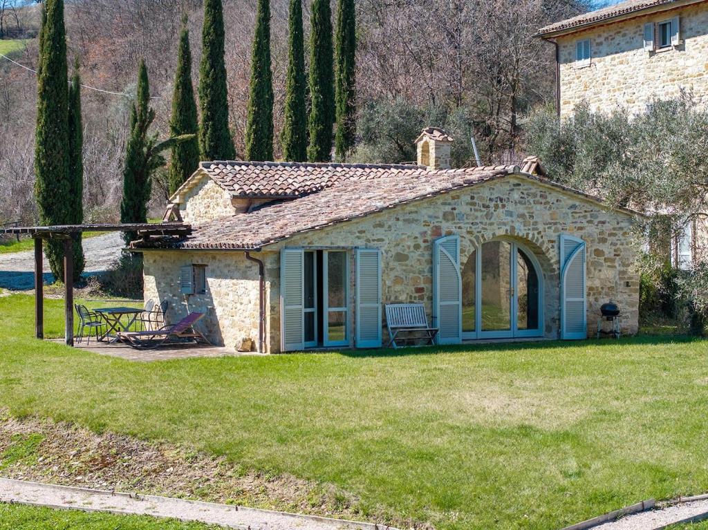 a small stone house in a field of grass at La Capella in Gubbio