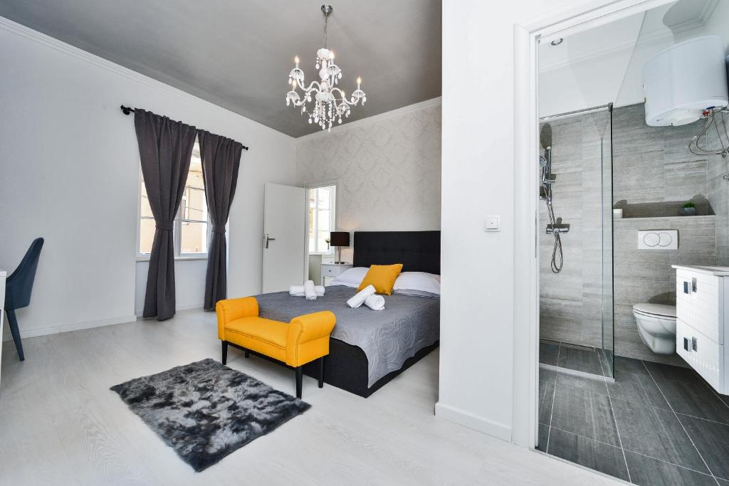 a bedroom with a bed and a yellow chair and a bathroom at Rooms Urban design in Zadar