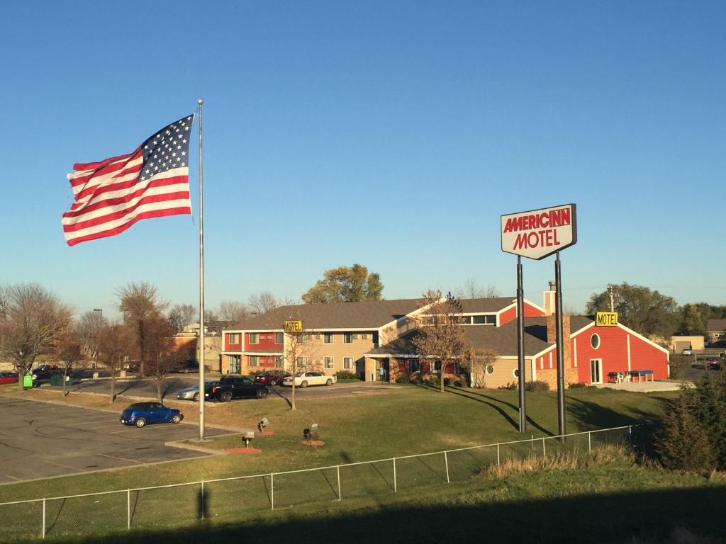 an american flag and a street sign in front of a motel at AmericInn Motel - Monticello in Monticello