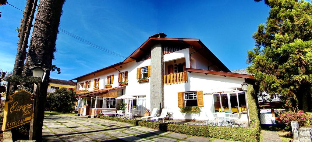 um grande edifício branco com um telhado de gambrel em Europa Hotel em Campos do Jordão