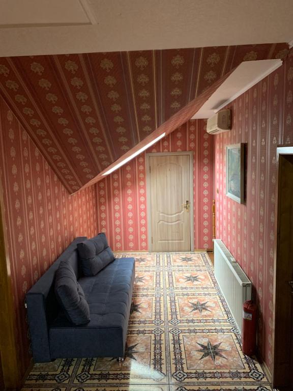 a living room with a blue couch in a room with red wallpaper at Hotel Мукачево in Mukacheve