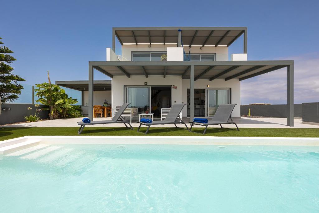 una casa con piscina di fronte a una casa di Villa Reflejo de Mar a Cotillo