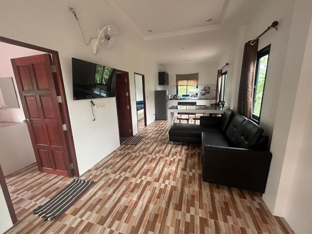 a living room with a black couch and a kitchen at Wimanthara houses in Thongsala