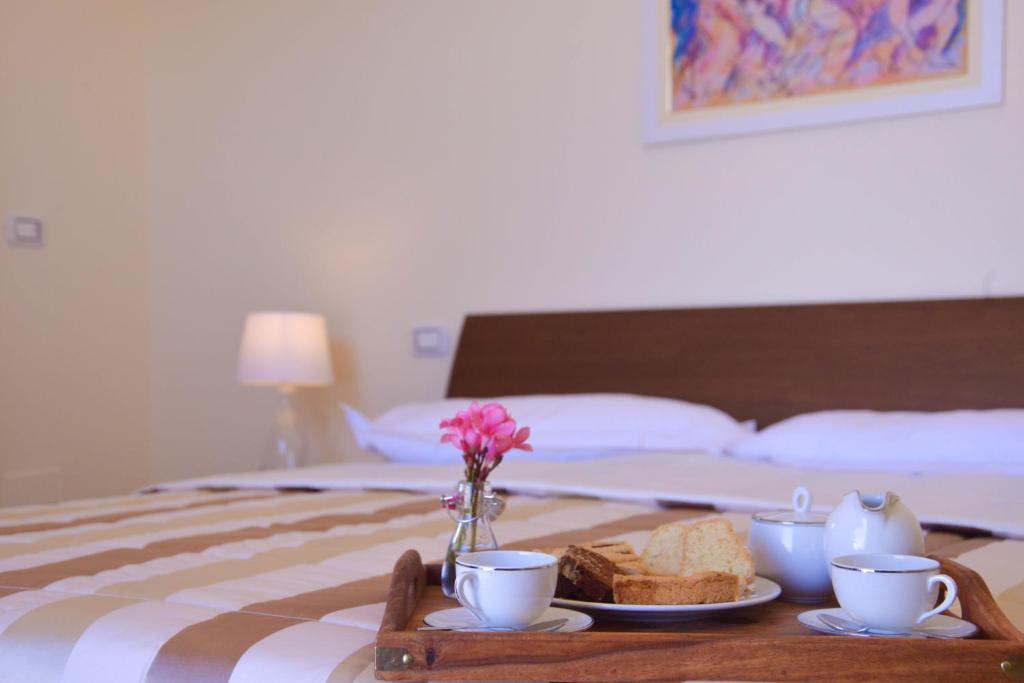San Donato di LecceにあるAgriturismo Puntarelleのベッドの上にサンドイッチとコーヒーカップ付きのトレイ