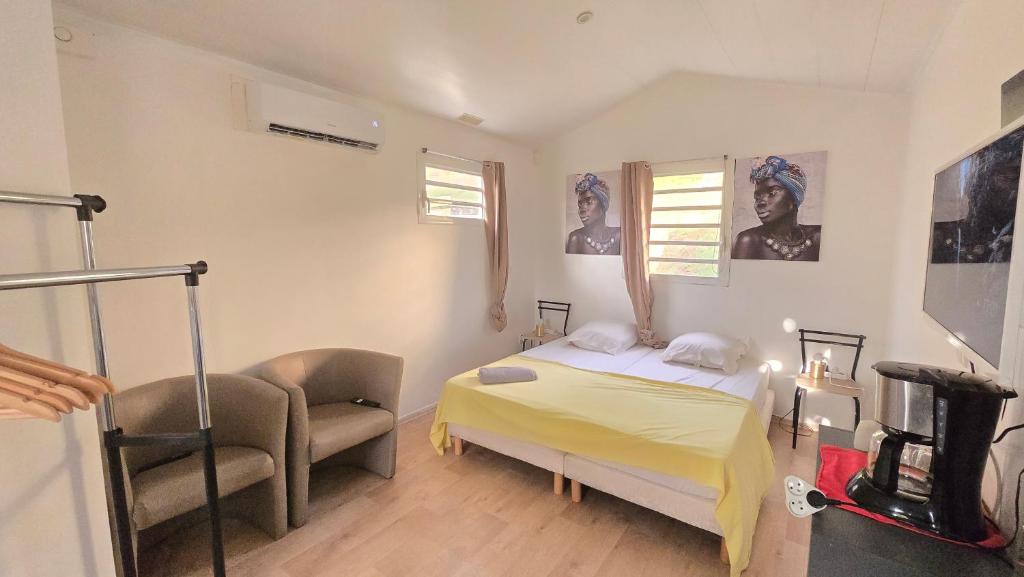 a bedroom with a bed and a chair in it at Tiny House & Tente Lodge, Le Paradis des Petits Voyageurs in Le Diamant
