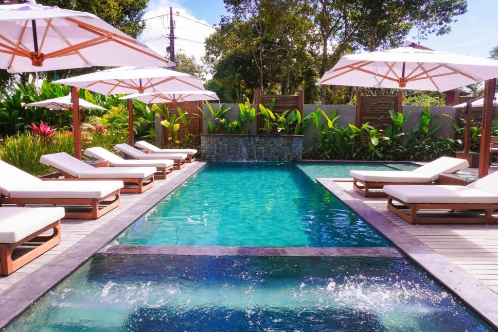 a swimming pool with lounge chairs and umbrellas at Aketá Hotel Boutique in Trancoso