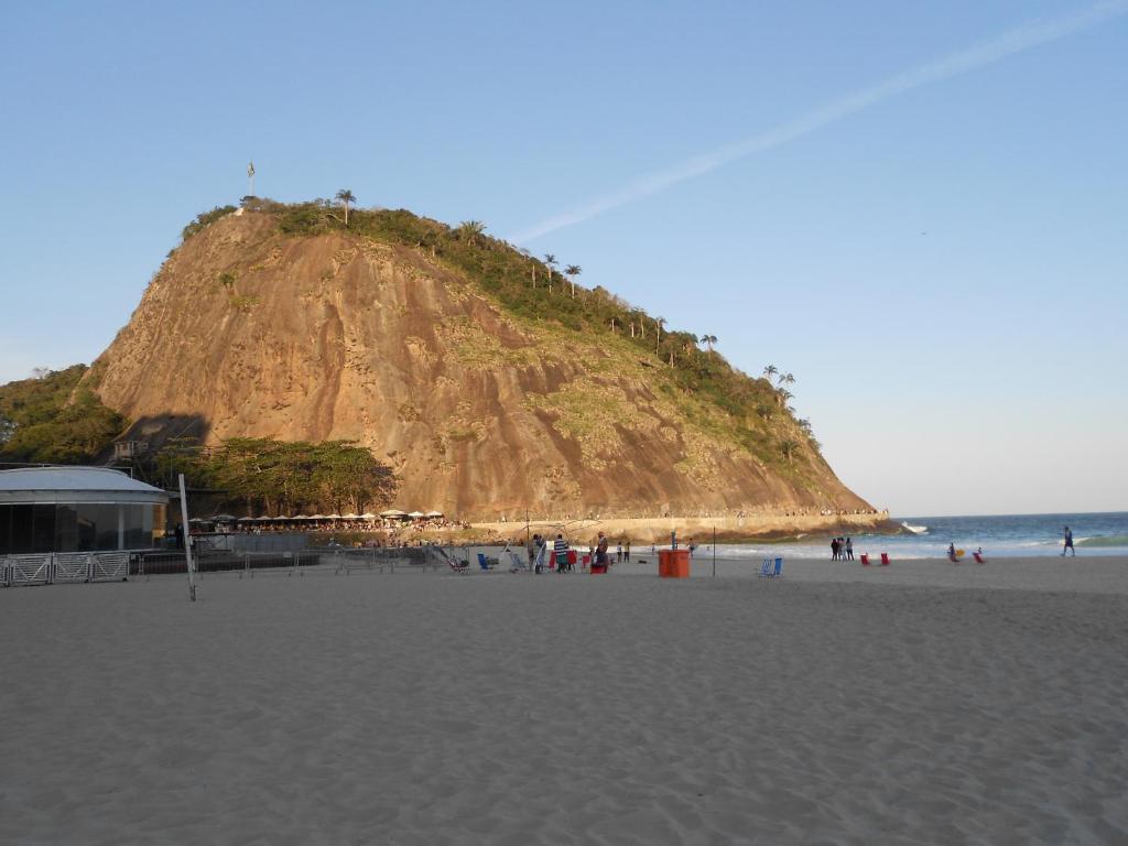 a sandy beach with a large hill in the ocean at Apartamento Princesa Izabel in Rio de Janeiro