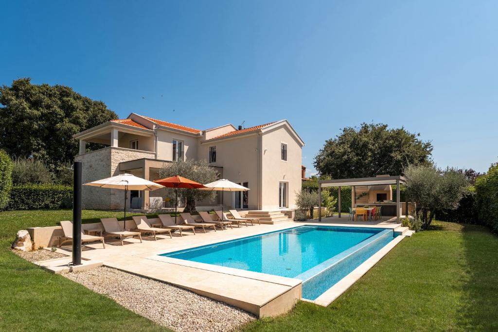 a villa with a swimming pool in front of a house at Villa MaK a family Oasis with heated Pool & Nature Views in Sveti Lovreč Pazenatički