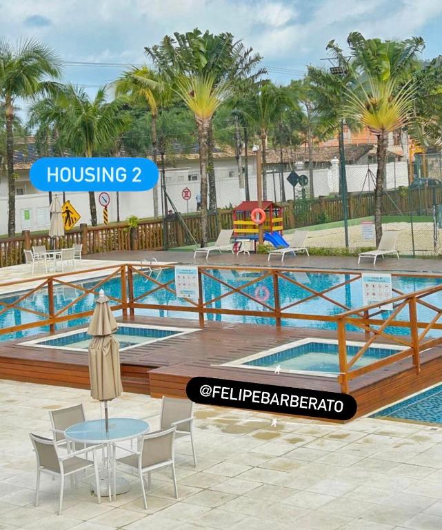 a pool with a table and chairs and palm trees at Maresias flat mata azul in Maresias