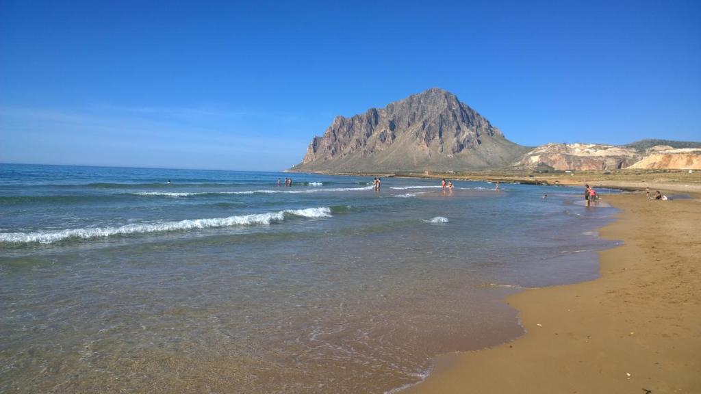 a group of people on a beach with a mountain in the background at Sul Golfo di Bonagia in Tonnara di Bonagia