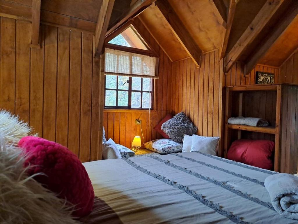 a bedroom with a large bed in a wooden room at Tiny house para dos in Las Trancas