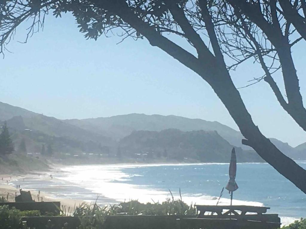 a beach with a table and an umbrella and the ocean at Gisborne, 3 Bedroom House, Beachfront, Wainui Beach in Gisborne