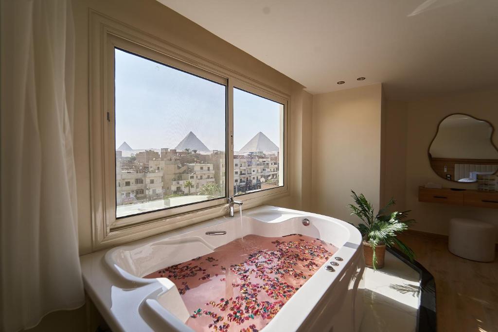 a bathroom with a large bath tub with a window at Merak Pyramids Hotel in Cairo
