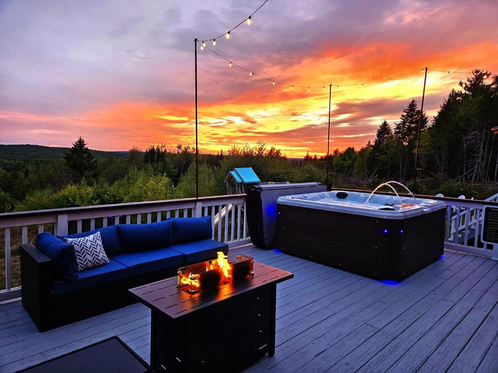 una vasca idromassaggio e un divano su un ponte con un tramonto di Bear Mountain Lodge. 560 Acre Wooded Estate. a Robbinston
