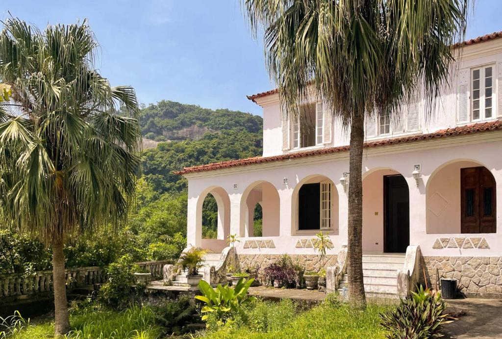 a white house with palm trees in front of it at Casa Rocha in Rio de Janeiro
