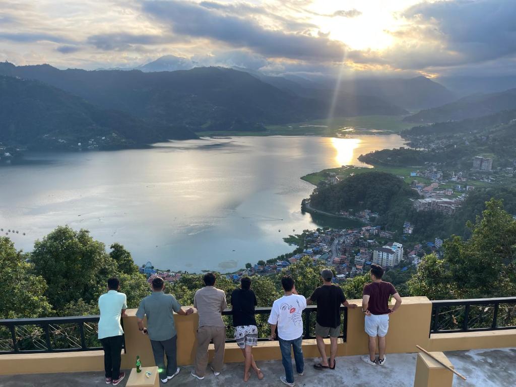 Un grupo de personas de pie en una cornisa con vistas a un lago. en Escape by feel good, en Pokhara