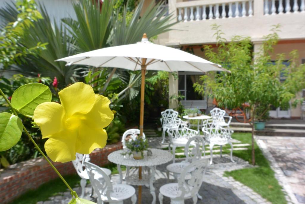 a patio with white tables and chairs and an umbrella at Bellalia 貝拉利亞 花蓮民宿 in Hualien City