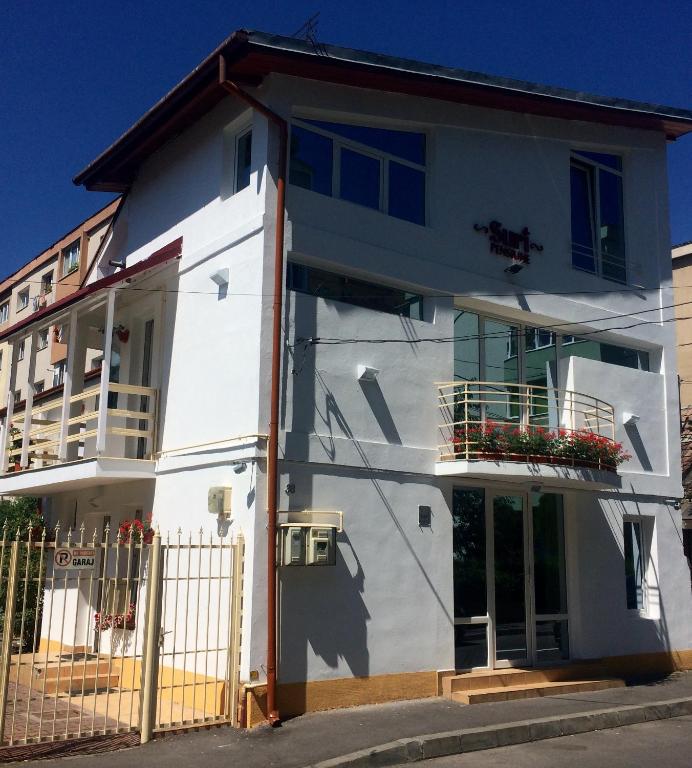 a white building with a fence in front of it at Suri Guesthouse in Braşov