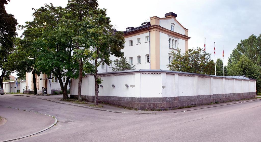 a white building with a fence in front of a street at Clarion Collection Hotel Bilan in Karlstad