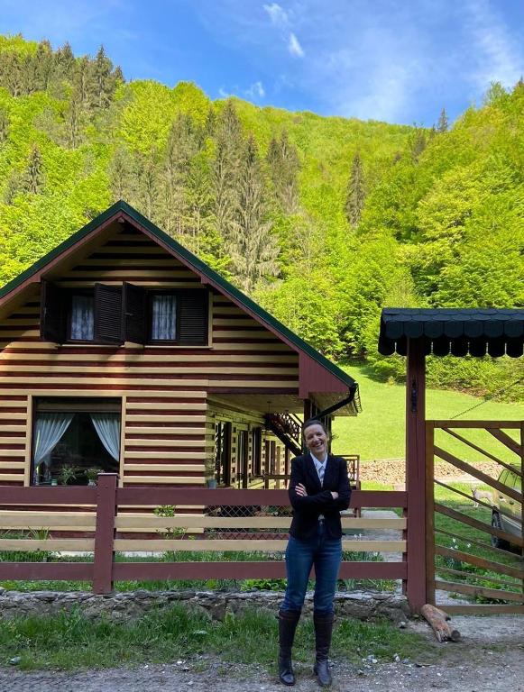 a woman standing in front of a cabin at Casa din Pădure in Petroşani