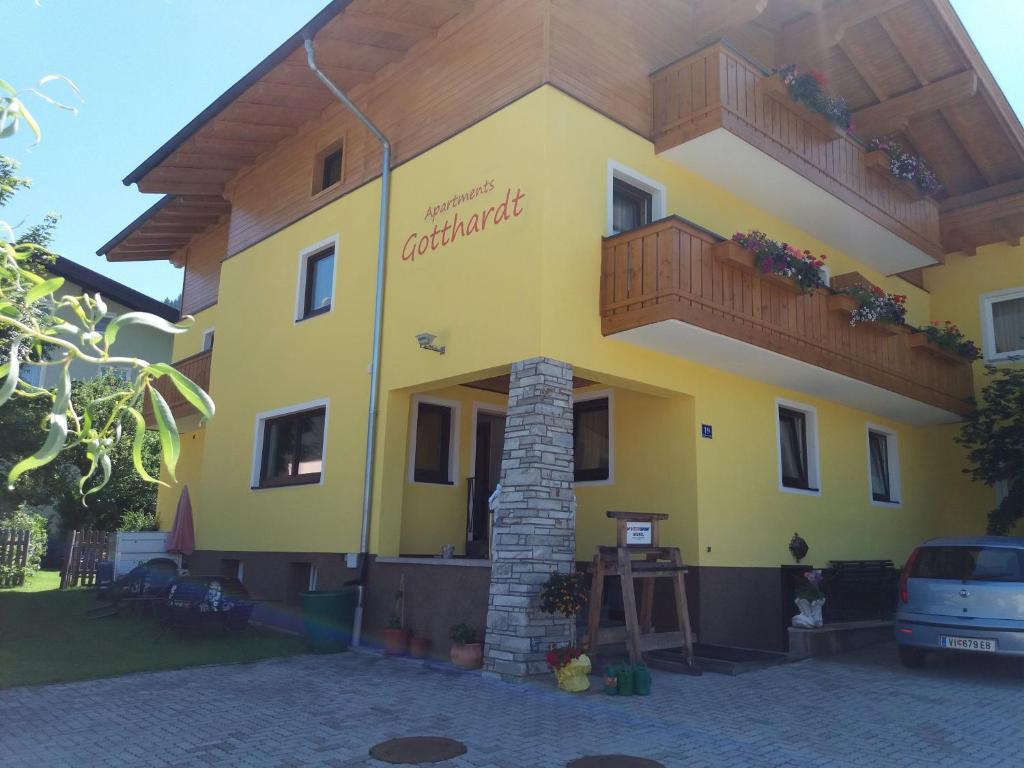 ein großes gelbes Gebäude mit Balkon in der Unterkunft Apartmenthaus Gotthardt in Kaprun