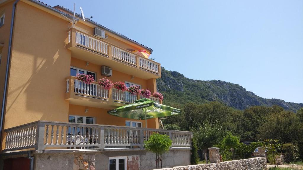 a yellow building with a balcony with an umbrella at Apartman "Anna" in Bribir