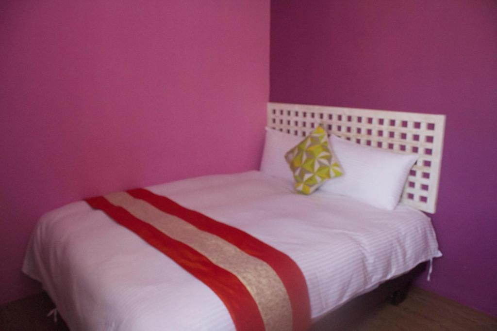 a bedroom with a white bed with purple walls at 文風小築Wen-Feng House-免費停車 in Kenting