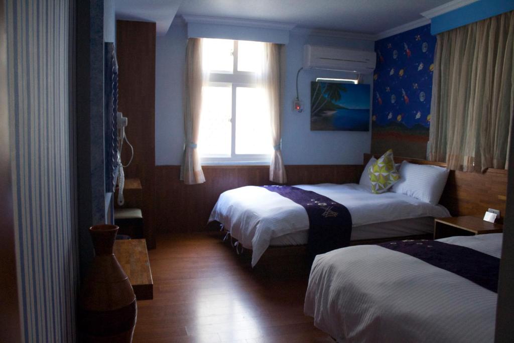 a hotel room with two beds and a window at 文風小築Wen-Feng House-免費停車 in Kenting