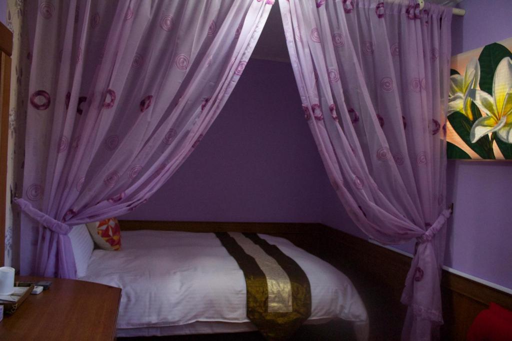 a bedroom with a bed with purple curtains at 文風小築Wen-Feng House-免費停車 in Kenting